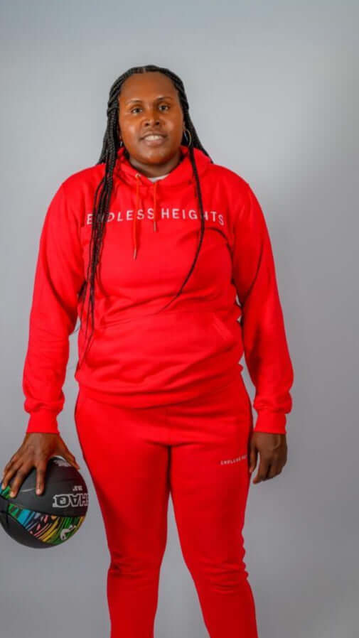 Model wearing Sky High Stacked jogging set in red, holding a basketball, showcasing the ENDLESS HEIGHTS collection.