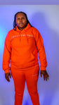 Taller Than LIfe Collection model wearing ENDLESS HEIGHTS tracksuit set in vibrant orange hoodie and matching pants.