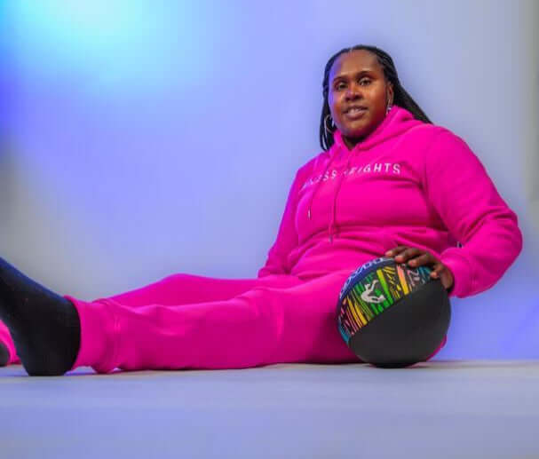 Taller Than LIfe Collection tracksuit set in pink worn by a person holding a colorful basketball.